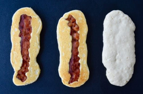 Griddle containing three pancake dippers with bacon