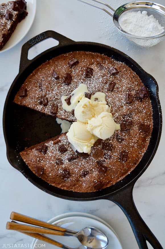 A cast-iron skillet brownie topped with ice cream and confectioners' sugar