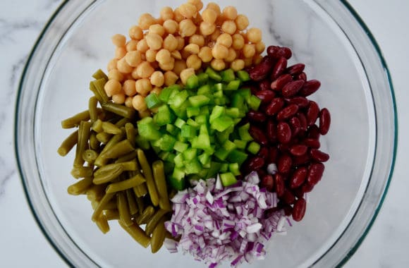 A glass bowl containing beans, onions and peppers