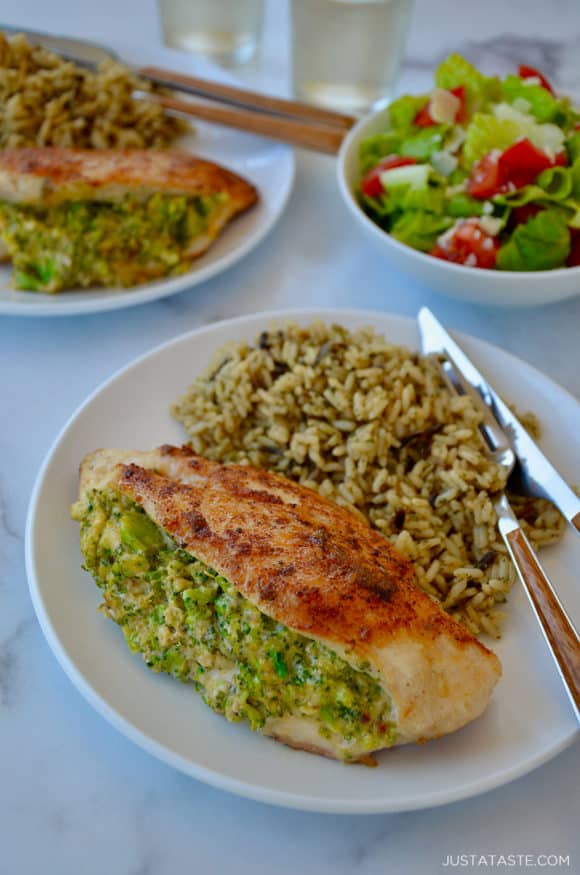 Two white plates with stuffed chicken breasts and wild rice with a salad on the side