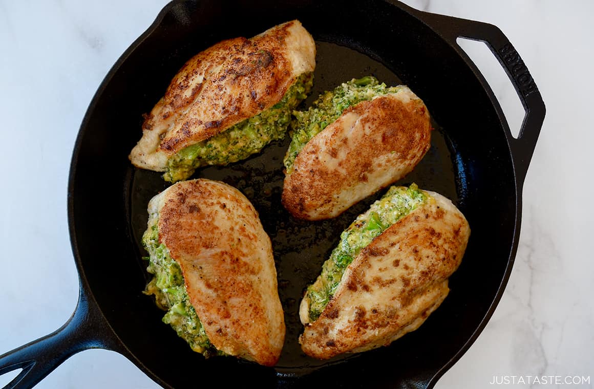 A cast-iron skillet containing seared, stuffed chicken breasts