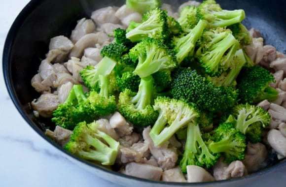 Skillet with diced chicken thighs and broccoli florets