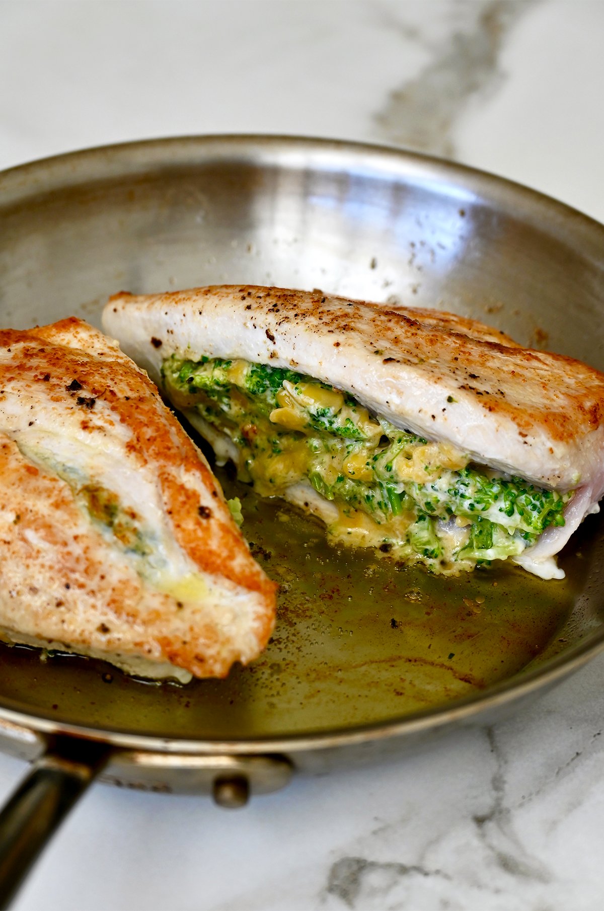 Seared stuffed chicken breast in a hot skillet.