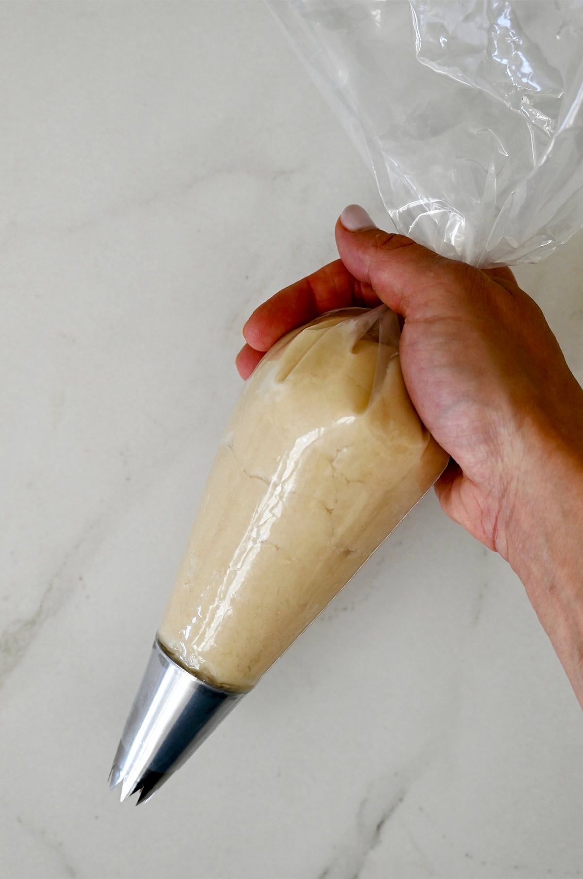 Churro dough in a heavy-duty plastic piping bag with an open star tip.