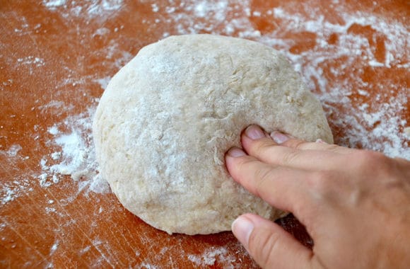 A ball of cinnamon roll dough on a wood cutting board