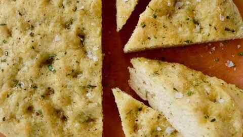 Four slices of Easy Homemade Focaccia (No Yeast) next to small bowls containing kosher salt and olive oil