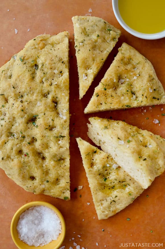 Four slices of Easy Homemade Focaccia (No Yeast) next to small bowls containing kosher salt and olive oil