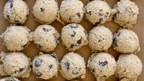 Rows of small scoops of edible cookie dough on brown parchment paper