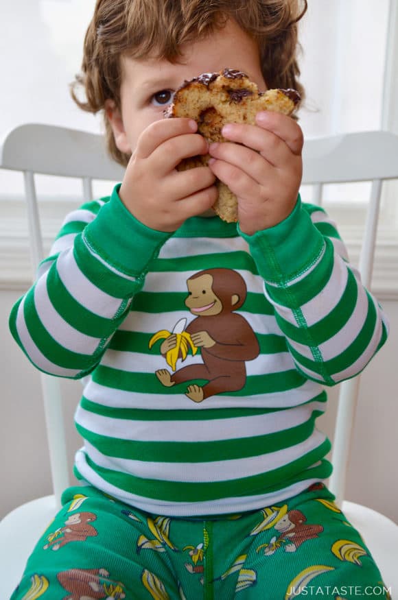 Child on chair holding a slice of banana bread up to his face