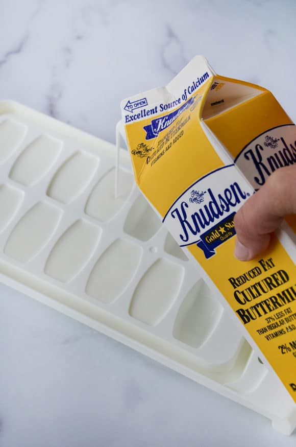 A carton of buttermilk being poured into an ice cube tray