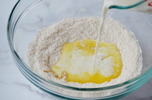 A glass bowl with milk and butter being poured in