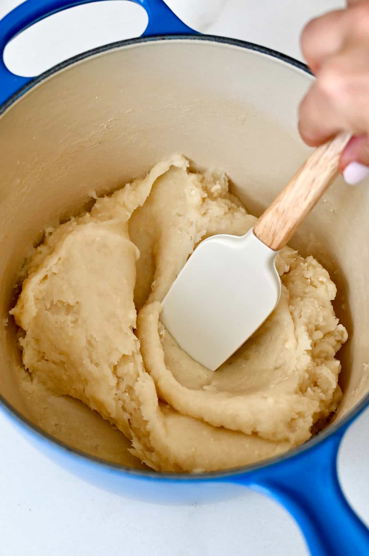 Churro dough in a saucepan with a spatula.