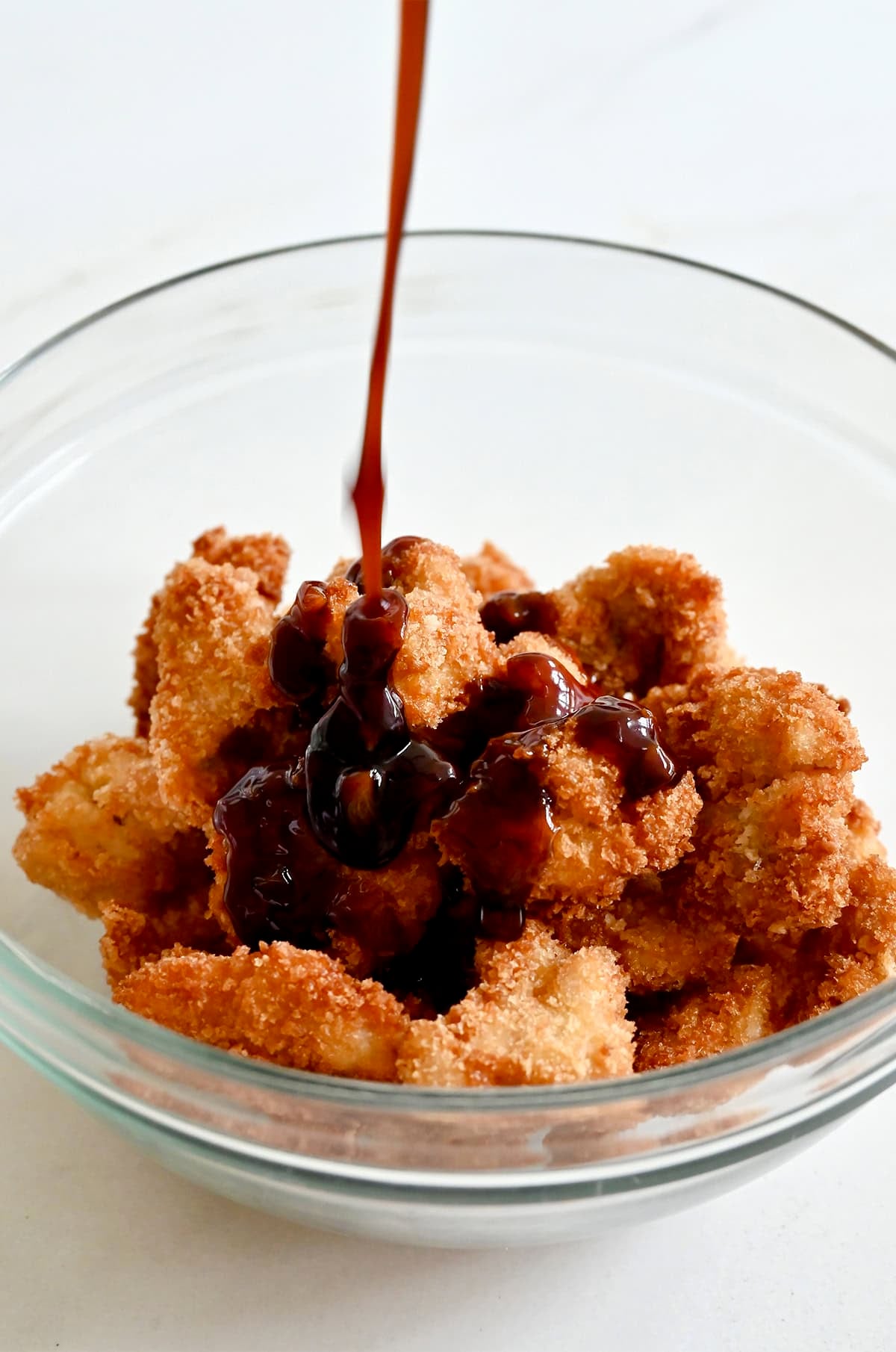 Coating fried chicken pieces in homemade sesame sauce.