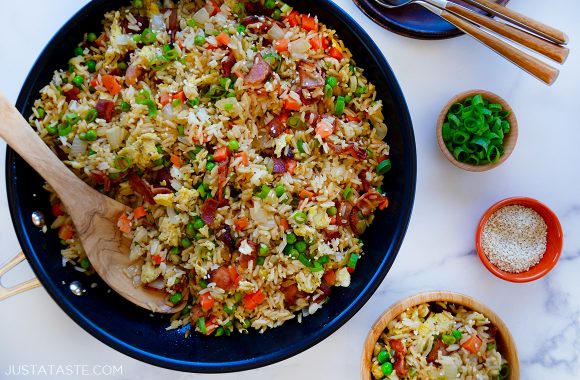 Wooden spoon in large skillet containing easy one-pan bacon and egg fried rice