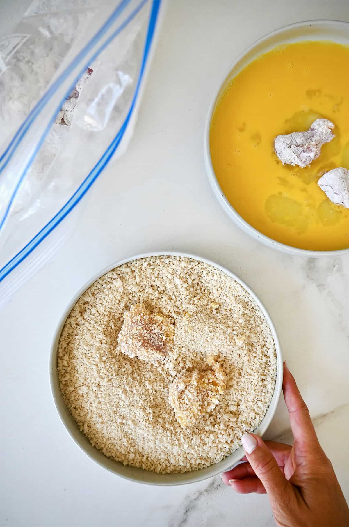 Coating chicken pieces in Panko breadcrumbs.