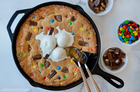 Spoons digging in to Halloween Candy Skillet Cookie topped with vanilla ice cream