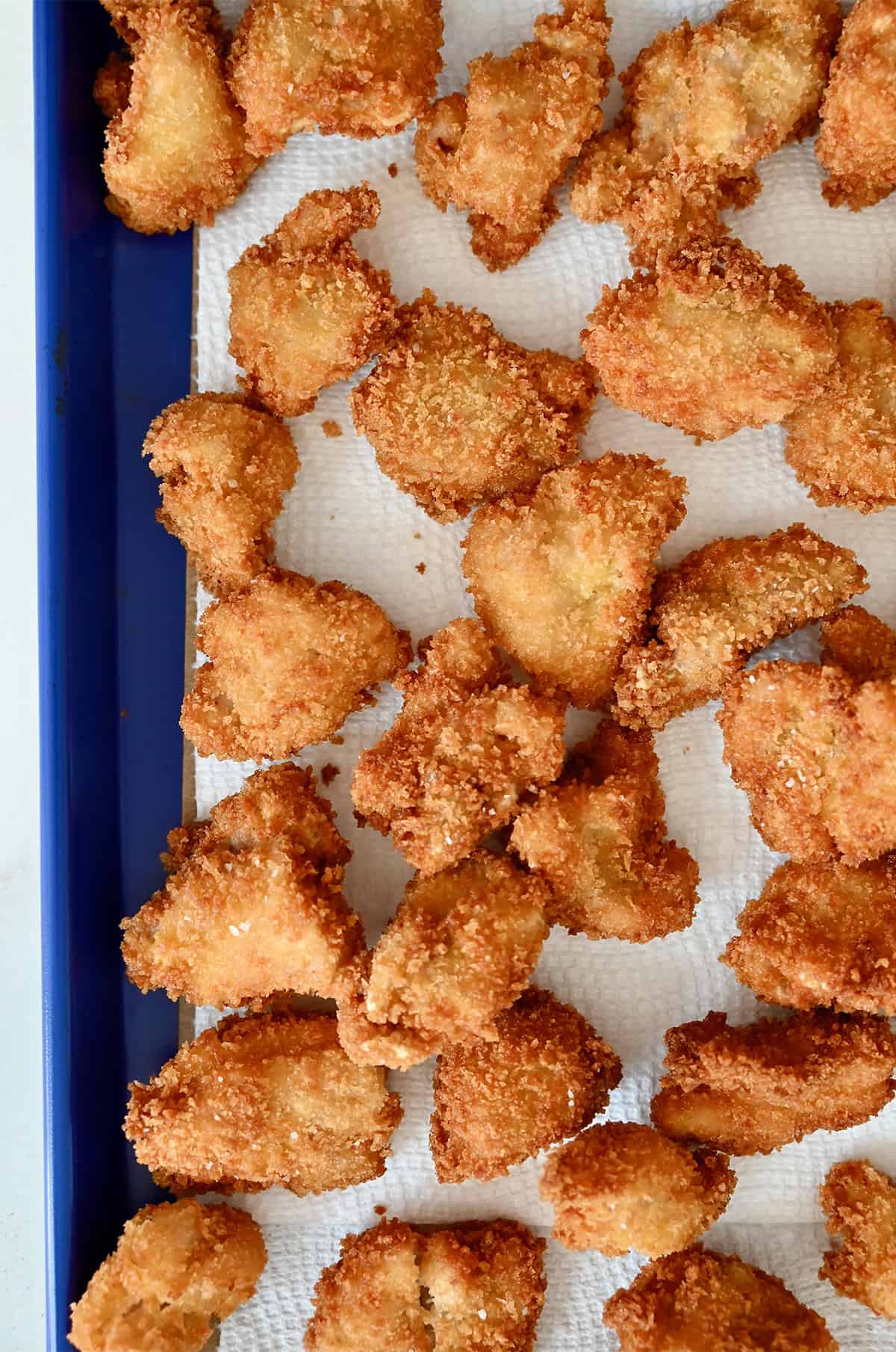 Fried chicken pieces draining on paper towels.