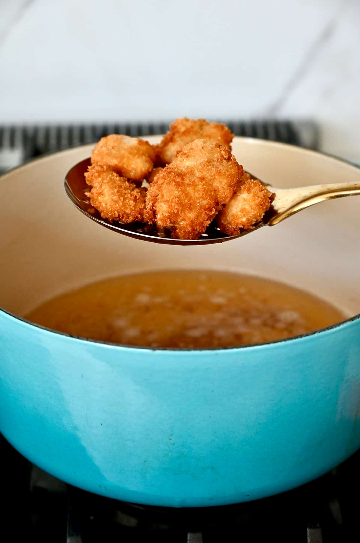 Frying bite-sized pieces of chicken thigh in hot oil.