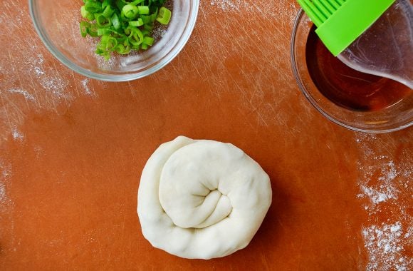 A cutting board with a scallion pancake coiled up