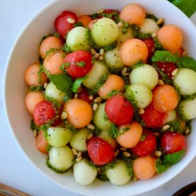 Top down view of white bowl containing easy melon salad with basil vinaigrette