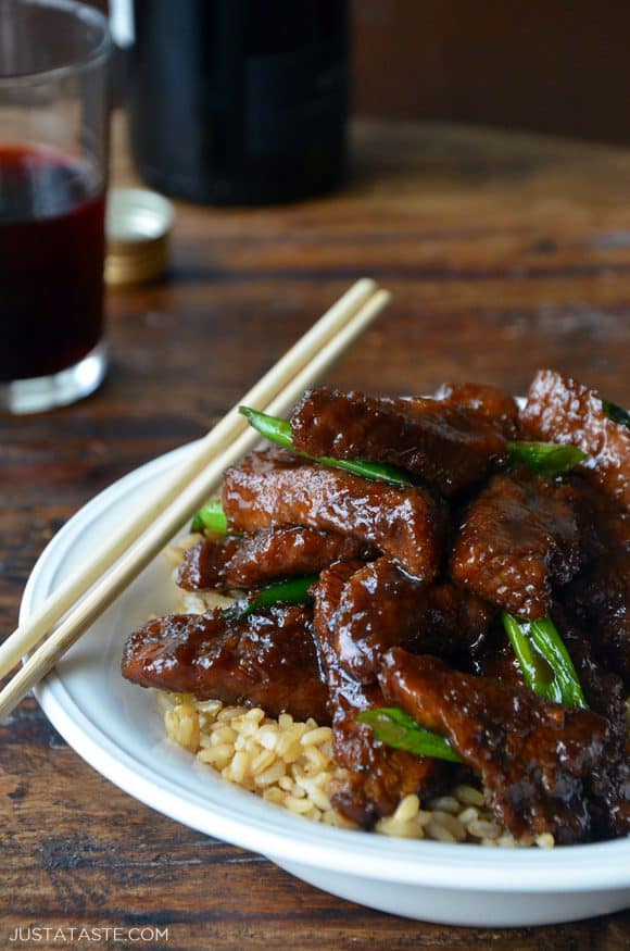 A white bowl containing Mongolian Beef on a bed of brown rice