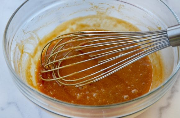 Bowl containing peanut dressing and whisk