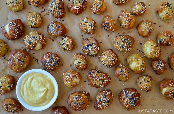 Pizza dough soft pretzel bites on a baking sheet with a white bowl containing mustard