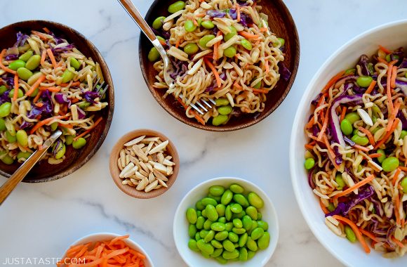 Easy ramen noodle salad in various sized bowls next to smaller bowls with edamame, slivered almonds and shredded carrots