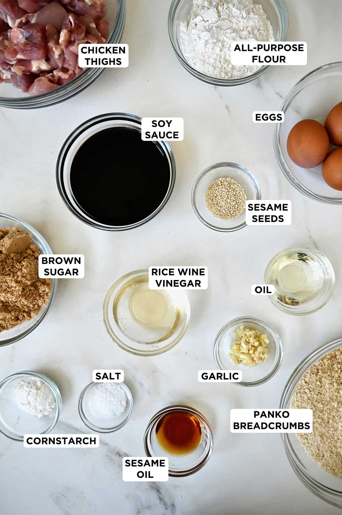 Ingredients to make sesame chicken in different sizes of glass prep bowls.