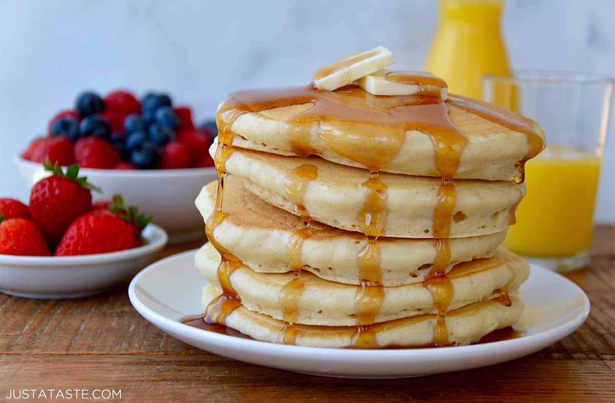 Stack of light and fluffy buttermilk pancakes topped with butter and maple syrup.