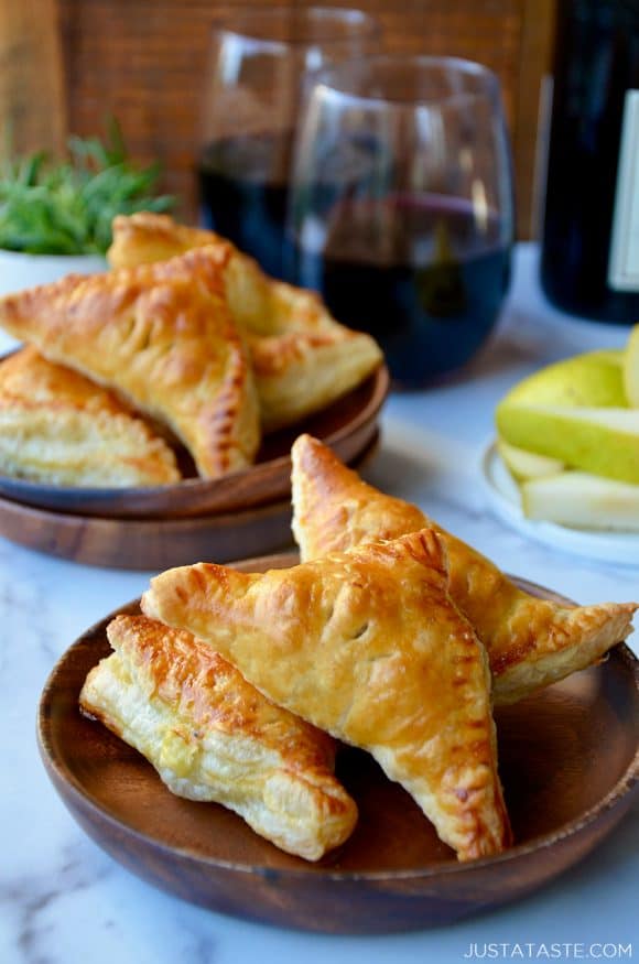 Mini Fruit and Cheese Turnovers on brown plate with glasses of red wine in background