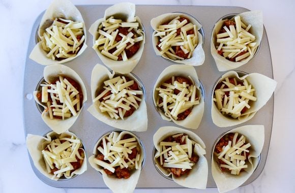 Top down view of muffin tin with unbaked lasagna cups