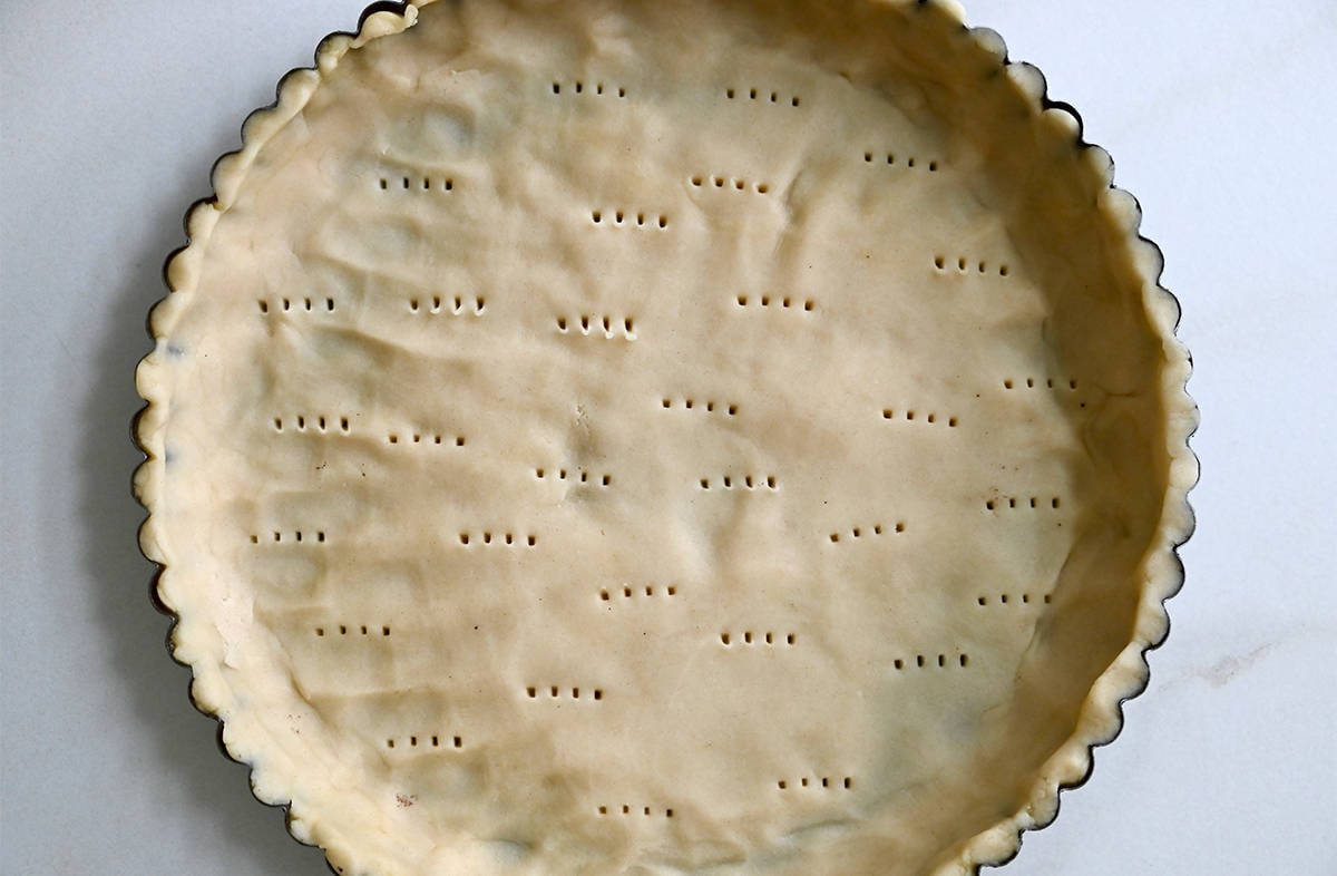 Dough pressed into a tart pan and that's been pricked all over with a fork.