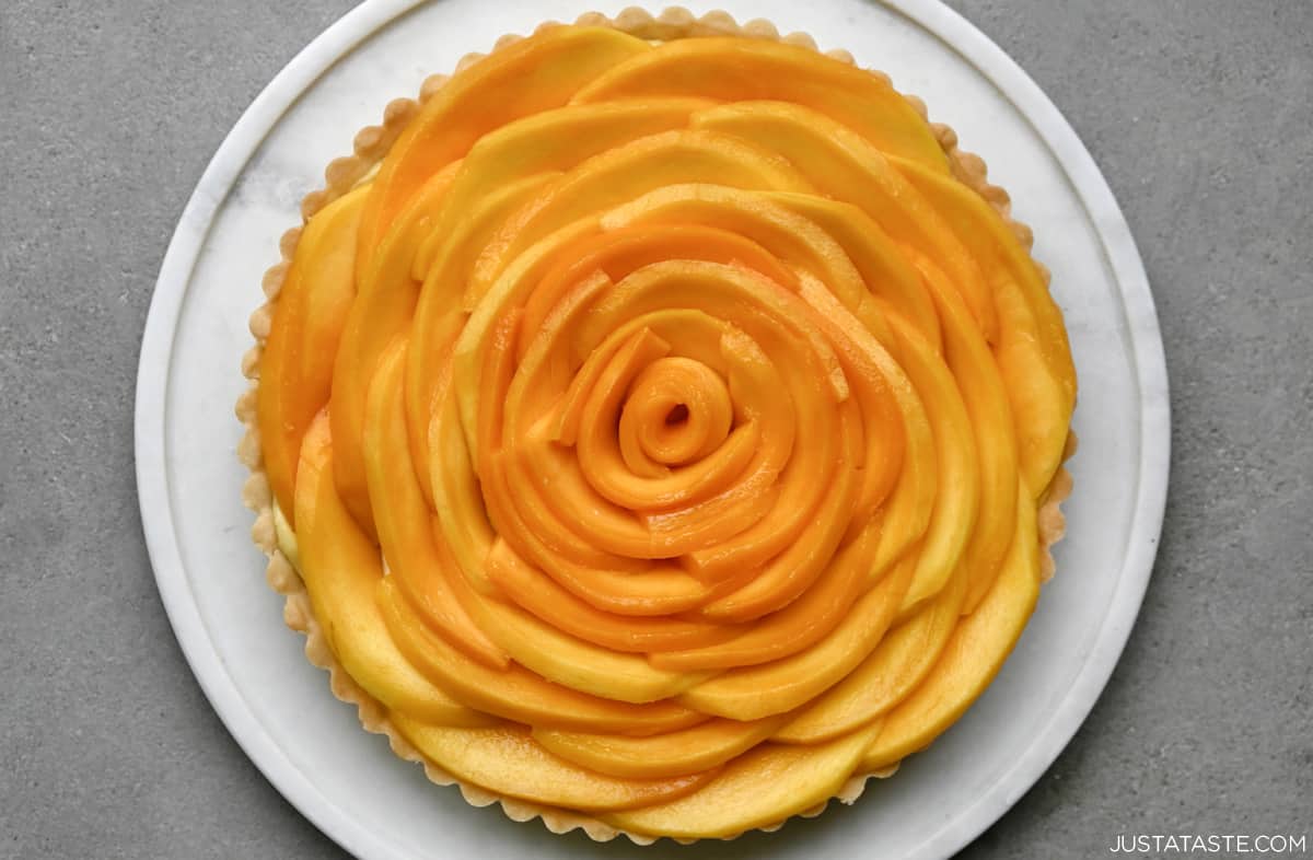 A mango tart that looks like a giant flower on a round serving tray.