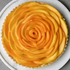 Easy mango tart with vanilla bean pastry cream on a white pie plate.