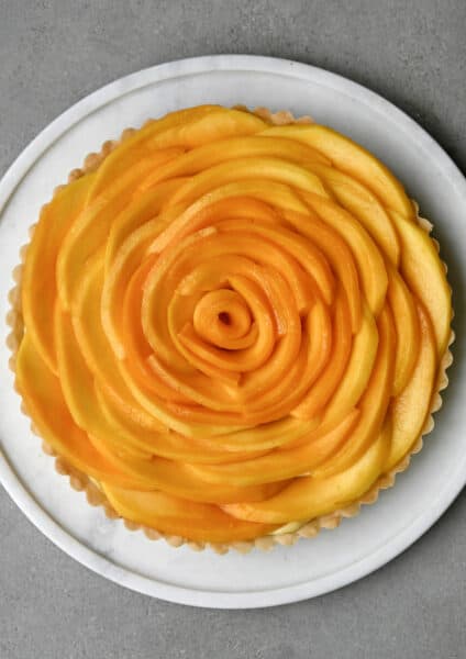 Easy mango tart with vanilla bean pastry cream on a white pie plate.
