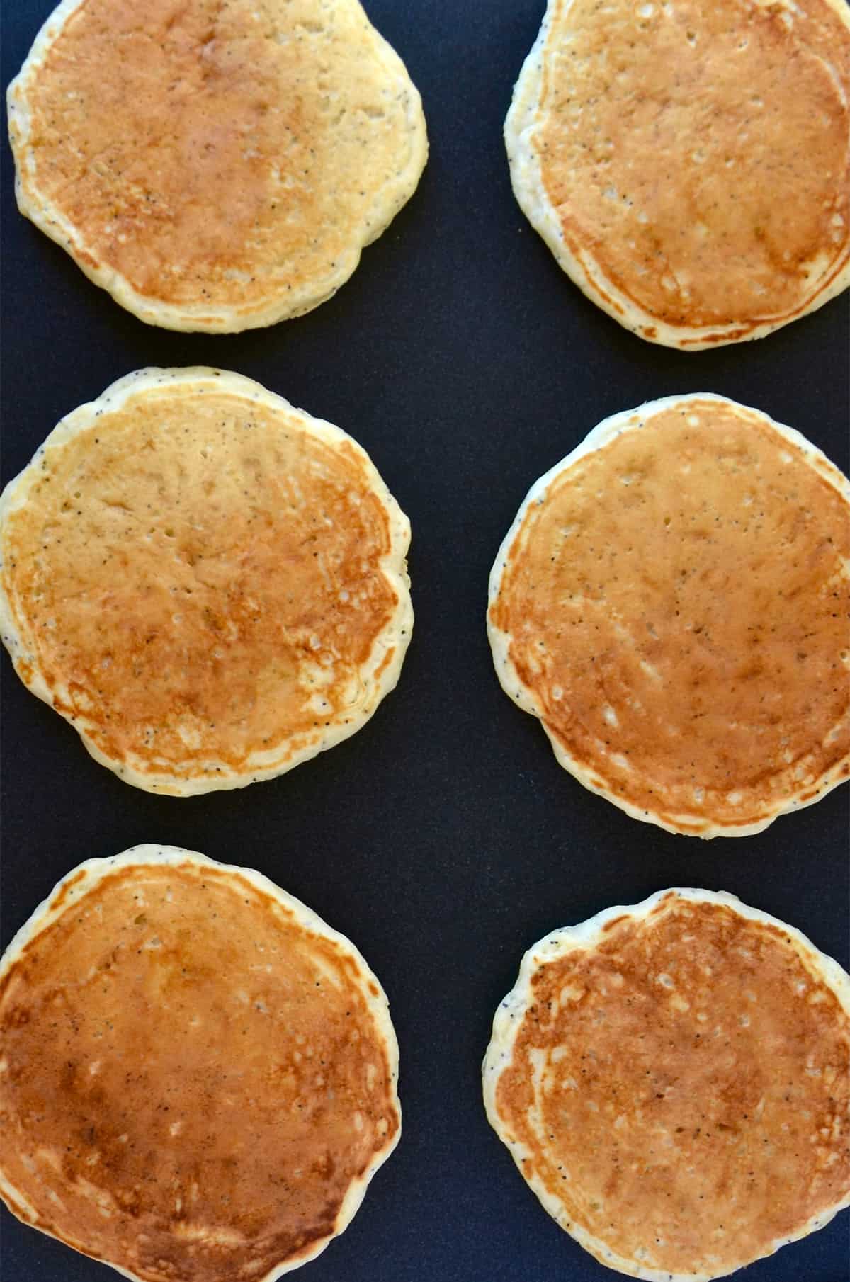 Two rows of golden brown pancakes on a griddle.