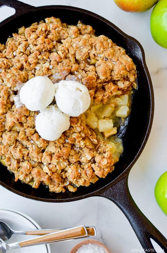 Cast-iron skillet with Easy Apple and Pear Crisp topped with three scoops of vanilla ice cream