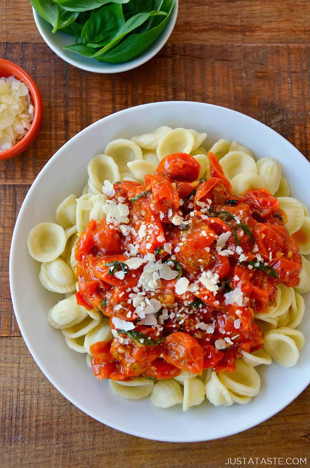 Cherry tomato pasta sauce over noodles on a white plate.