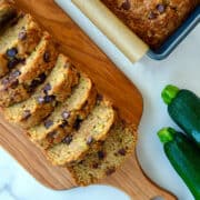 Top-down view of a sliced loaf of Chocolate Chip Zucchini Bread next to two zucchinis.