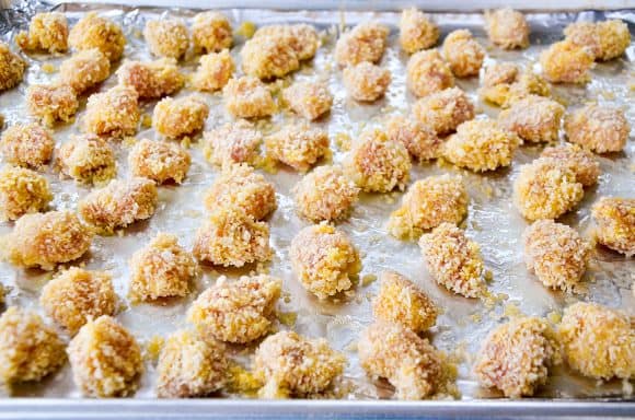 Unbaked chicken bites atop a baking sheet lined with foil