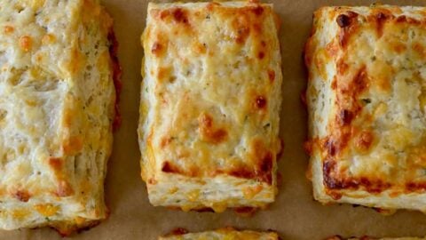 Rows of The Best Cheddar Biscuits on parchment paper-lined baking sheet