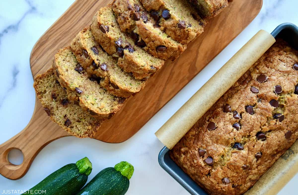 Two loaves of zucchini chocolate chip bread next to two zucchini.