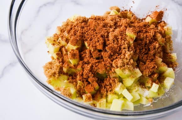 Clear bowl containing diced apples and cinnamon