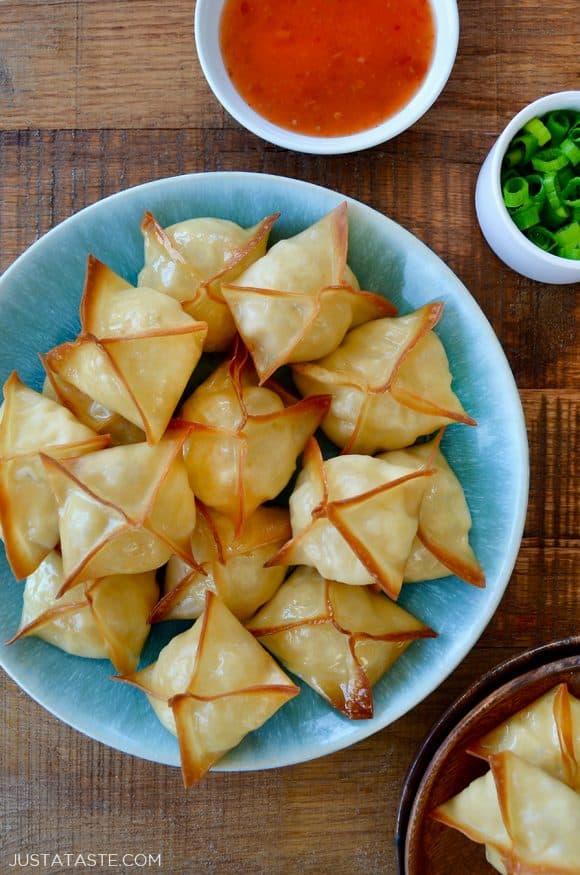 Top down view of Crispy Baked Crab Rangoon on blue plate next to small ramekin containing sweet and sour sauce