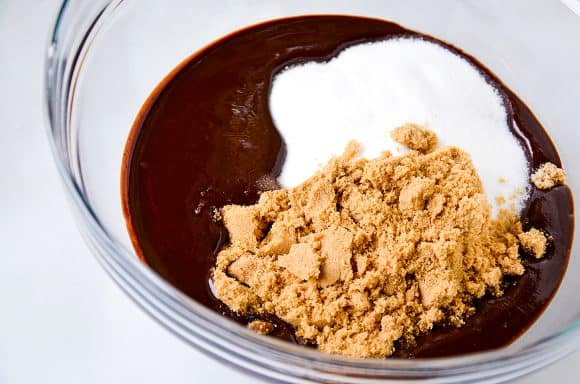 Melted chocolate, white sugar and brown sugar in a glass bowl