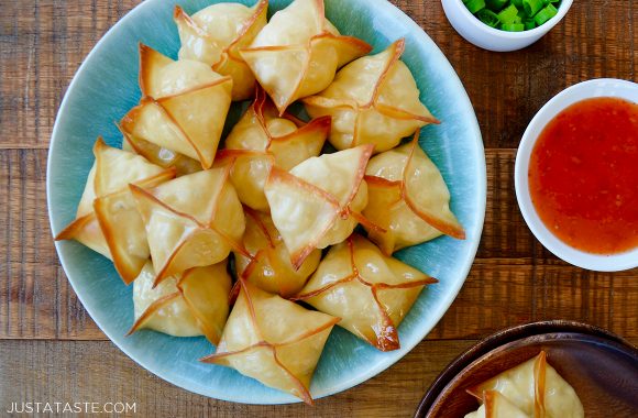 Easy baked crab rangoon on blue serving plate next to a small bowl with sweet and sour sauce