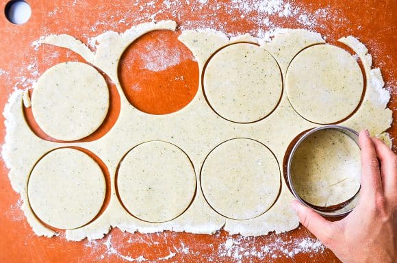 Hand with circle cookie cutter cutting pie dough