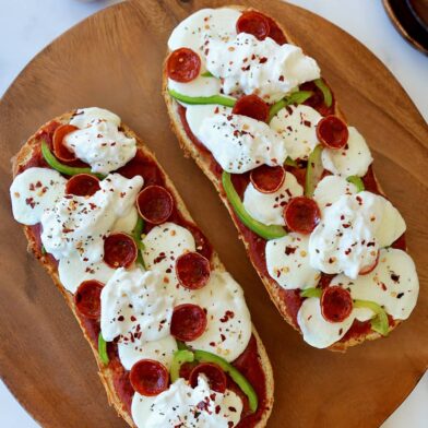 The Best French Bread Pizza with Burrata on wooden cutting board