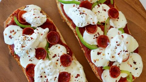 The Best French Bread Pizza with Burrata on wooden cutting board